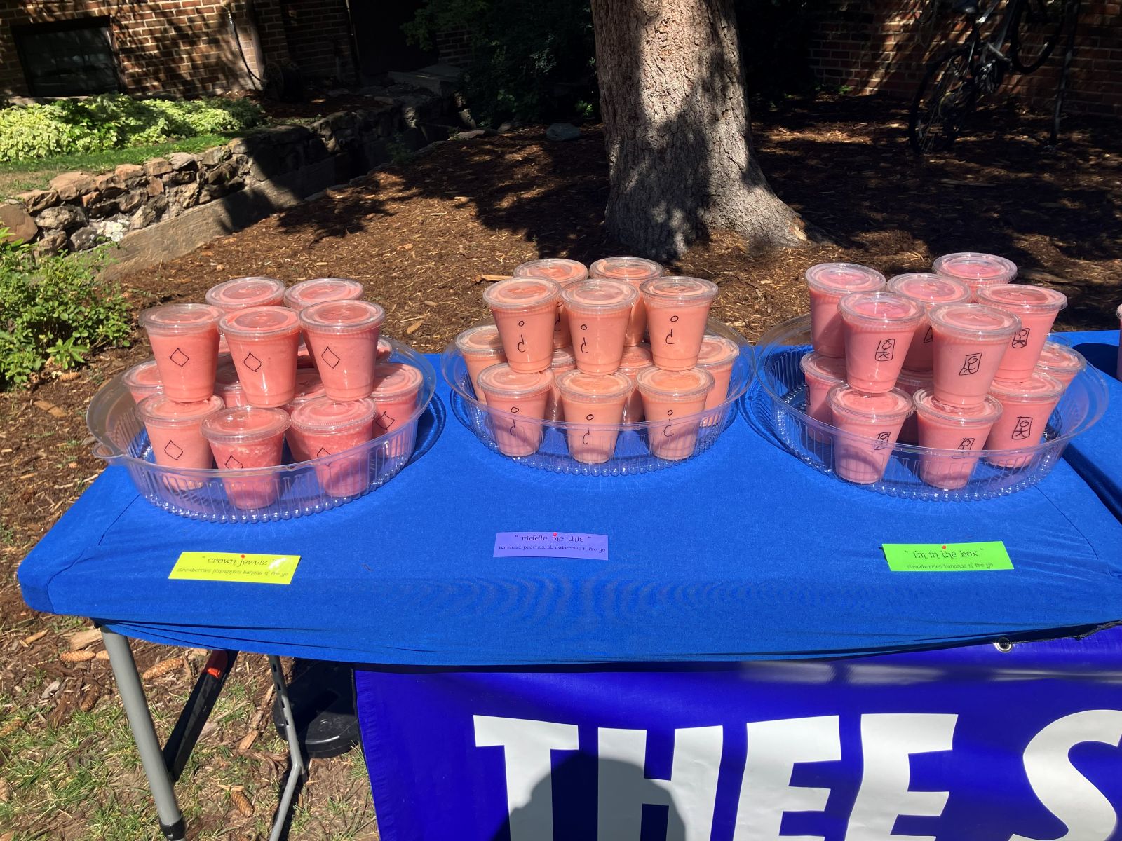 Catering table with trays of labeled sample smoothies