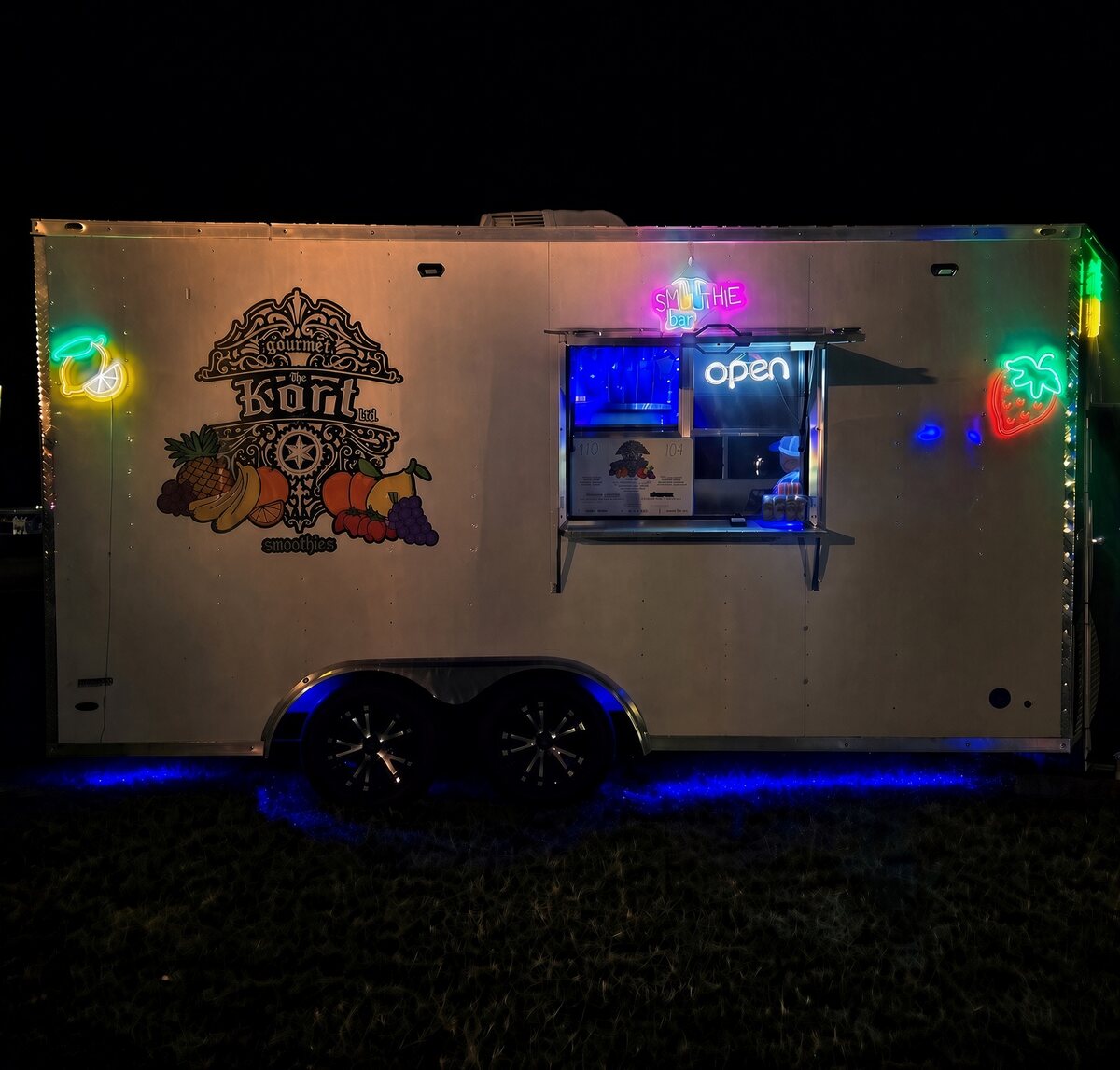 Thee Smoothie Kort trailer lit up with neon at an evening event